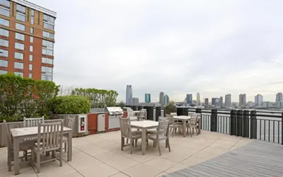 a patio with tables and chairs and a view of the city at Blueground Battery Park City rooftop nr Hudson River NYC-291 in New York