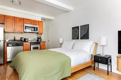 a bedroom with a large bed and a kitchen at Blueground Upper West Side wd nr Central Park NYC-1860 in New York