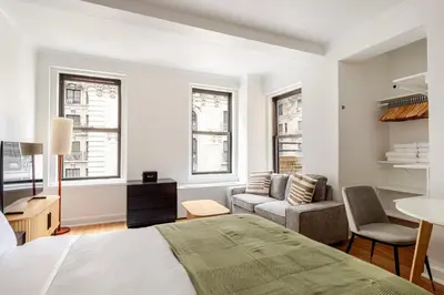 a bedroom with a bed and a couch and windows at Blueground Upper West Side wd nr Central Park NYC-1860 in New York