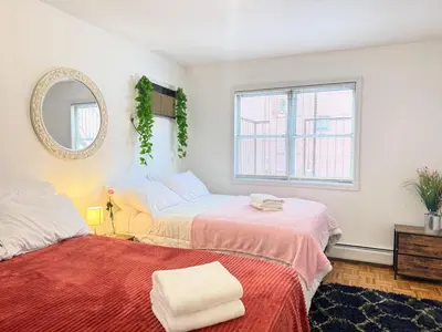 a bedroom with two beds and a mirror at Huge Place Minutes from NYC Parking Available in Guttenberg