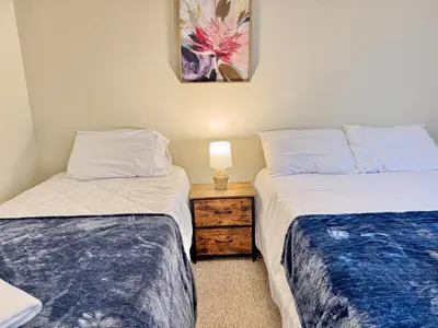 a room with two beds and a night stand with a lamp at Huge Place Minutes from NYC Parking Available in Guttenberg