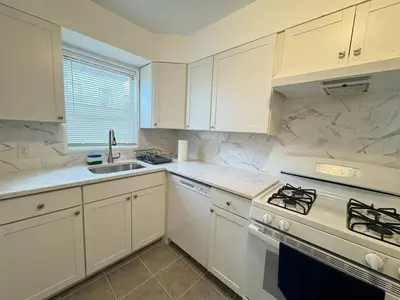 a kitchen with white cabinets and a stove top oven at Huge Place Minutes from NYC Parking Available in Guttenberg