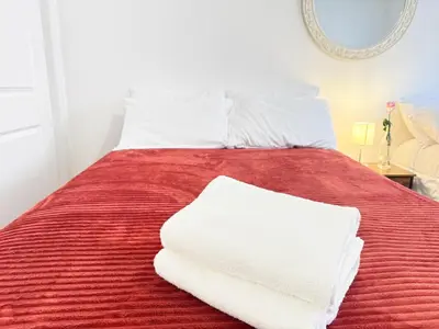 a bed with red sheets and white pillows on it at Huge Place Minutes from NYC Parking Available in Guttenberg