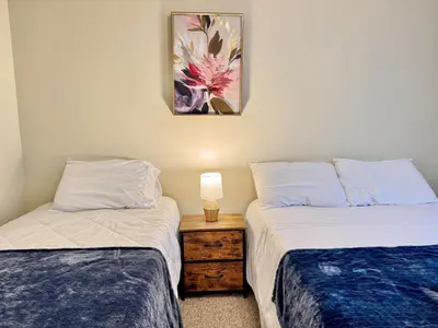 a bedroom with two beds and a table with a lamp at Huge Place Minutes from NYC Parking Available in Guttenberg