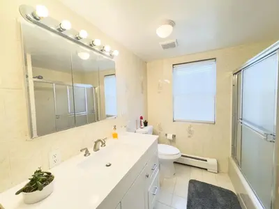 a bathroom with a sink and a toilet and a mirror at Spacious and Convinient near NYC Parking Available in Guttenberg