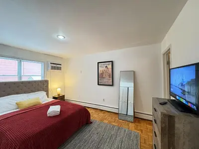 a bedroom with a bed and a flat screen tv at Spacious and Convinient near NYC Parking Available in Guttenberg