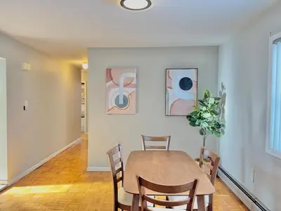 a dining room with a table and chairs and paintings at Spacious and Convinient near NYC Parking Available in Guttenberg