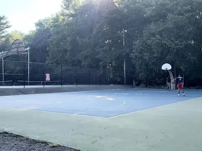 a person holding a basketball hoop on a tennis court at Modern 4 Bedroom Home with Sauna and Game Room in Gated Lake Community in East Stroudsburg