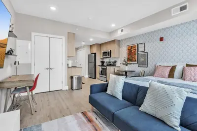 a living room with a bed and a blue couch at Floor To Ceiling Windows- Bridge Views - Studio in Philadelphia