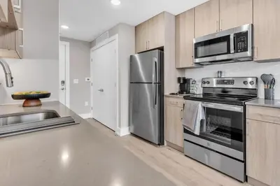 a kitchen with stainless steel appliances and wooden cabinets at Floor To Ceiling Windows- Bridge Views - Studio in Philadelphia