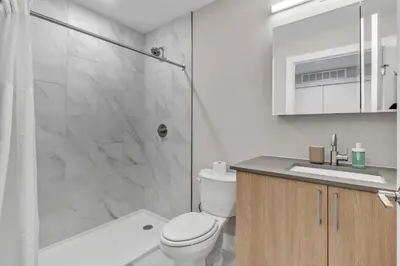 a bathroom with a toilet and a shower and a sink at Floor To Ceiling Windows- Bridge Views - Studio in Philadelphia