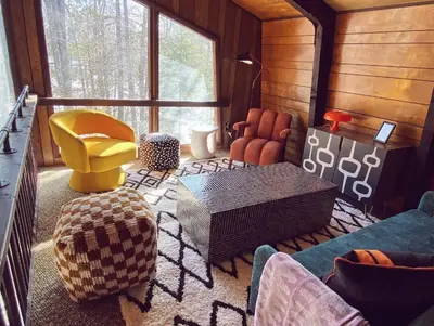 a living room with a yellow chair and a table at Designer Poconos Chalet I Ski, Skate, Lakes, Family-Friendly in Lake Ariel
