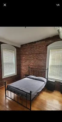 a bed in a room with a brick wall at The LOFT in Rahway