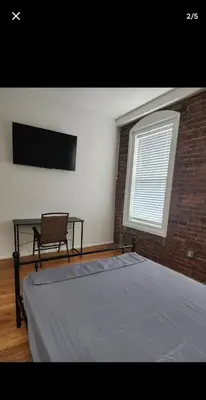 a bedroom with a bed and a chair and a window at The LOFT in Rahway