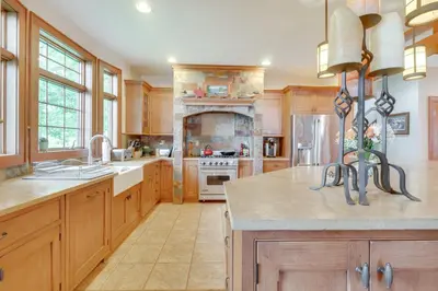 a large kitchen with wooden cabinets and a fireplace at Luxe Family Home on Orange Lake with Private Dock! in Newburgh