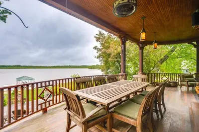 a deck with a table and chairs and a view of the water at Luxe Family Home on Orange Lake with Private Dock! in Newburgh