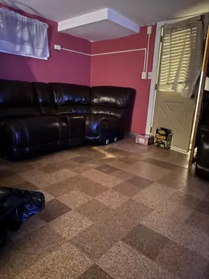 a living room with a black leather couch and pink walls at Quiet Harrisburg home in Harrisburg
