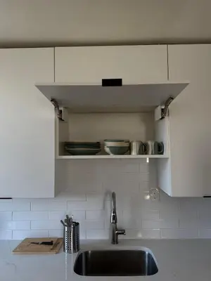 a kitchen with a sink and a shelf with dishes at 15 mins to NYC-Great Apartment Great for Family in West New York