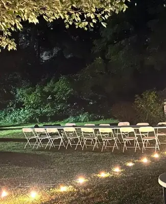 a group of tables and chairs in a park at night at The Villa Farm