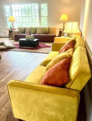 a living room with a yellow couch with pillows on it at The Villa Farm