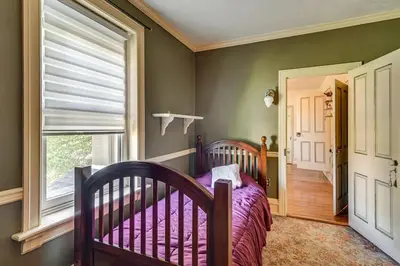 a bedroom with a crib and a large window at Historic Main Street Getaway