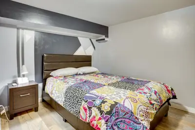 a bedroom with a bed with a colorful blanket and a night stand at Apt 2 Mi to Prudential Center and Dtwn Newark! in Newark