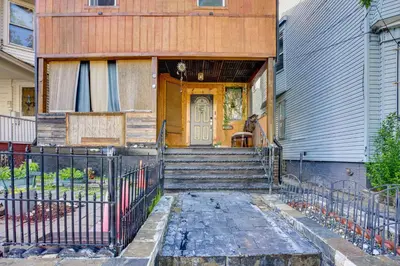 a house with a wooden door and stairs in front at Apt 2 Mi to Prudential Center and Dtwn Newark! in Newark