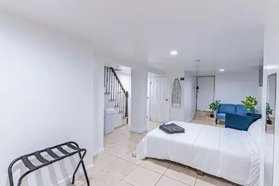 a white bedroom with a bed and a blue couch at Newark NJ Private Suite NYC Path Train in Newark