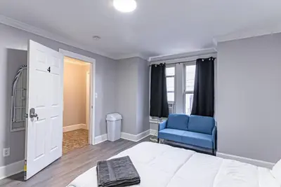 a bedroom with a white bed and a blue chair at Private BR Trains EWR USA Mall Penn Station in Newark
