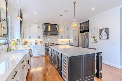 a large kitchen with white cabinets and a large island at Bergen County NYC Bus Malls in Maywood