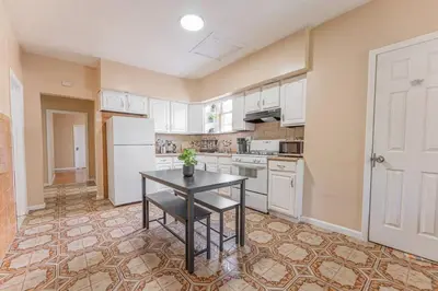a kitchen with a table and a white refrigerator at Private BR Wlk to NYC Train 3 in Bayonne