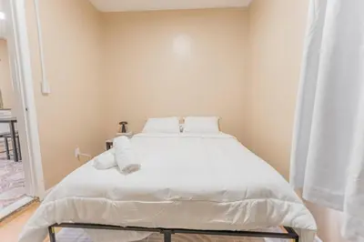 a bedroom with a bed with white sheets and pillows at Private BR Wlk to NYC Train 3 in Bayonne
