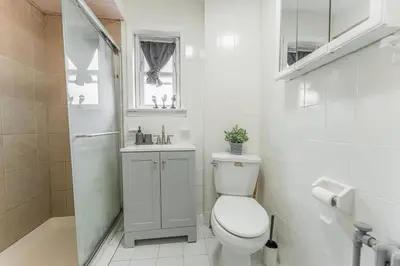 a white bathroom with a toilet and a sink at NYC Train EWR Liberty Park 2 in Bayonne