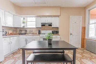 a kitchen with white cabinets and a table with a potted plant at Roomy 4br Walk to Transit connect to NYC in Bayonne