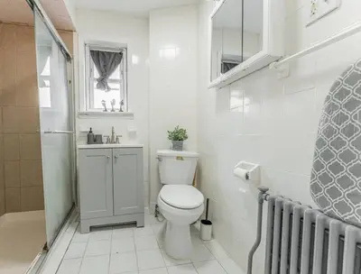 a white bathroom with a toilet and a sink at Roomy 4br Walk to Transit connect to NYC in Bayonne