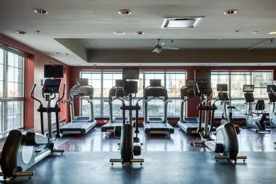 a gym with rows of tread machines in a room at Blueground Hudson Exchange pool nr Liberty Park NYC-1800 in New York