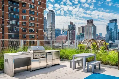 a grill and a table on a patio with a city skyline at Blueground Lincoln Square rooftop nr Central Park NYC-1217 in New York