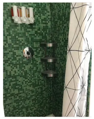 a shower with a green tiled wall with paper towels at Hudson Guest House in Jersey City