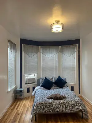 a bedroom with a bed with blue pillows at Hudson Guest House in Jersey City