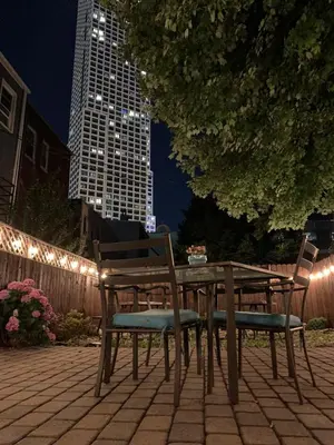 a wooden table and chairs sitting on a patio at night at Hudson Guest House in Jersey City