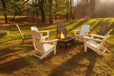three chairs and a fire pit in the grass at Hot Tub & Theater Haven-Lake and Ski Retreat in Blakeslee