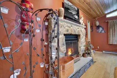 a fireplace in a living room with a stone wall at Arrowhead Lodge Walk to Lake & Private Dock in Pocono Lake