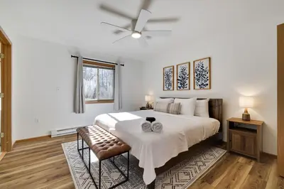 a white bedroom with a bed with two candles on it at Serene Escape at Big Bass Lake & Pool Access in Clifton
