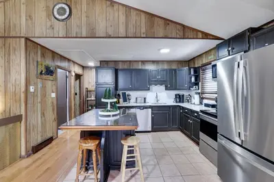 a kitchen with wooden cabinets and a stainless steel refrigerator at Bear Haven Cabin - Epic Game RoomLakeFire Pit in Gouldsboro