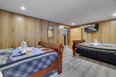 two beds in a room with wooden walls at Bear Haven Cabin - Epic Game RoomLakeFire Pit in Gouldsboro