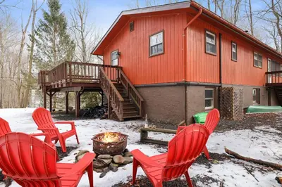 a group of red chairs in front of a house at Bear Haven Cabin - Epic Game RoomLakeFire Pit in Gouldsboro