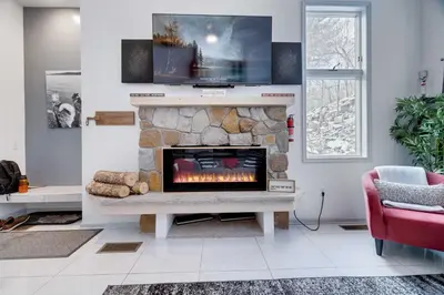 a living room with a fireplace with a tv above it at Husky Hideaway-Hot Tub, 1 Mile Lake & Ski in Lake Harmony