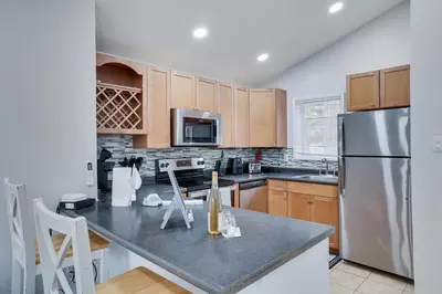 a kitchen with wooden cabinets and a stainless steel refrigerator at Lakeside Escape Hot Tub Private Dock Ski in Tobyhanna