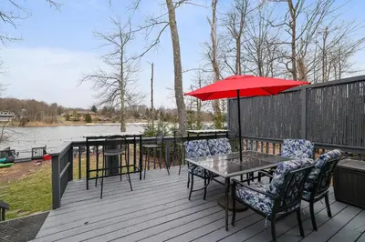 a table and chairs with an umbrella on a deck at Lakeside Escape Hot Tub Private Dock Ski in Tobyhanna