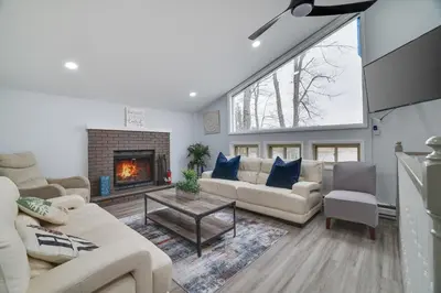 a living room with white furniture and a fireplace at Lakeside Escape Hot Tub Private Dock Ski in Tobyhanna